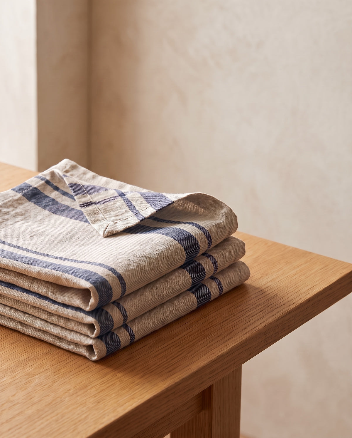 Righe napkins in Notte: four washed linen napkins with navy woven stripes, folded and stacked on an oak table
