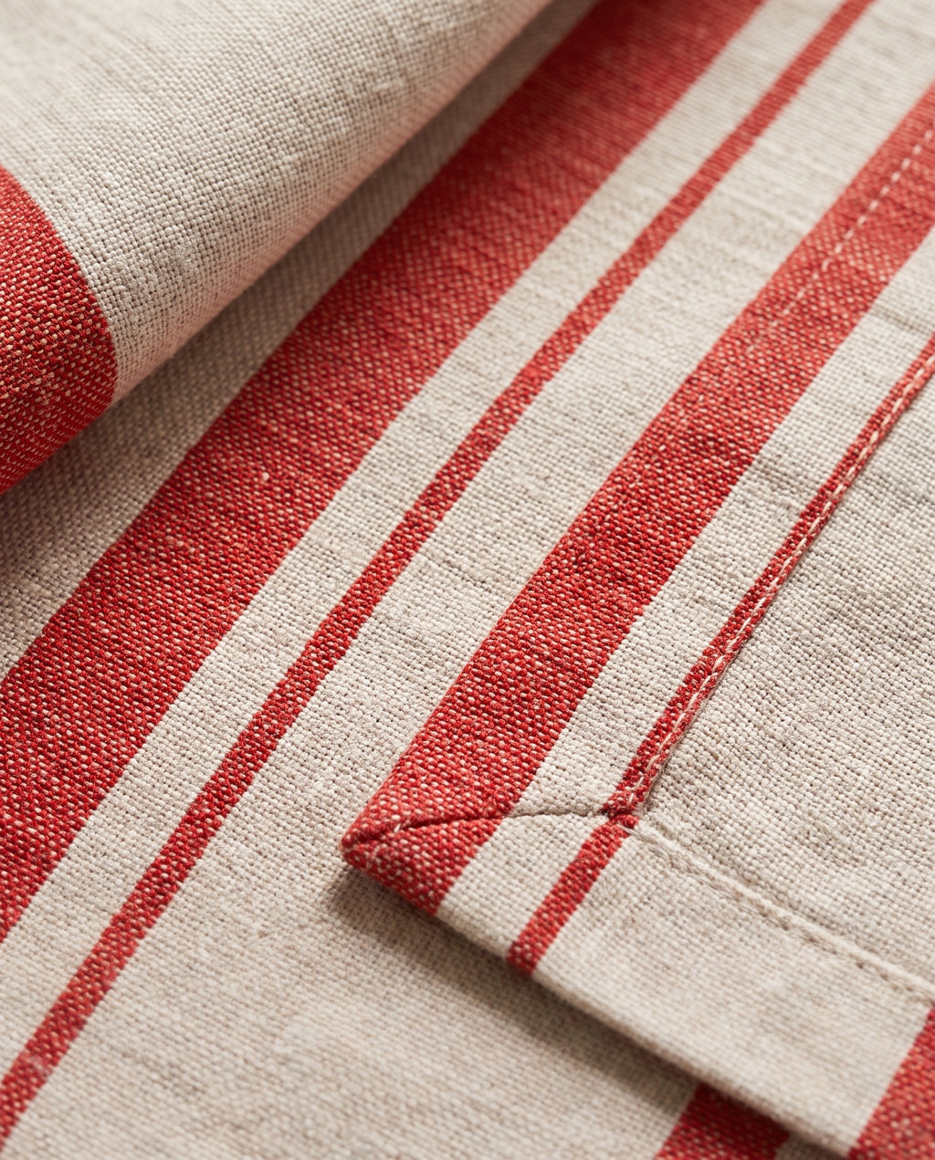 Close-up of the woven red stripe, the double-folded hem and the mitred corner of a Righe napkin