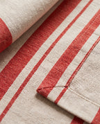 Close-up of the woven red stripe, the double-folded hem and the mitred corner of a Righe napkin
