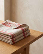 Righe napkins in Pomodoro: four washed linen napkins with red woven stripes, folded and stacked on an oak table