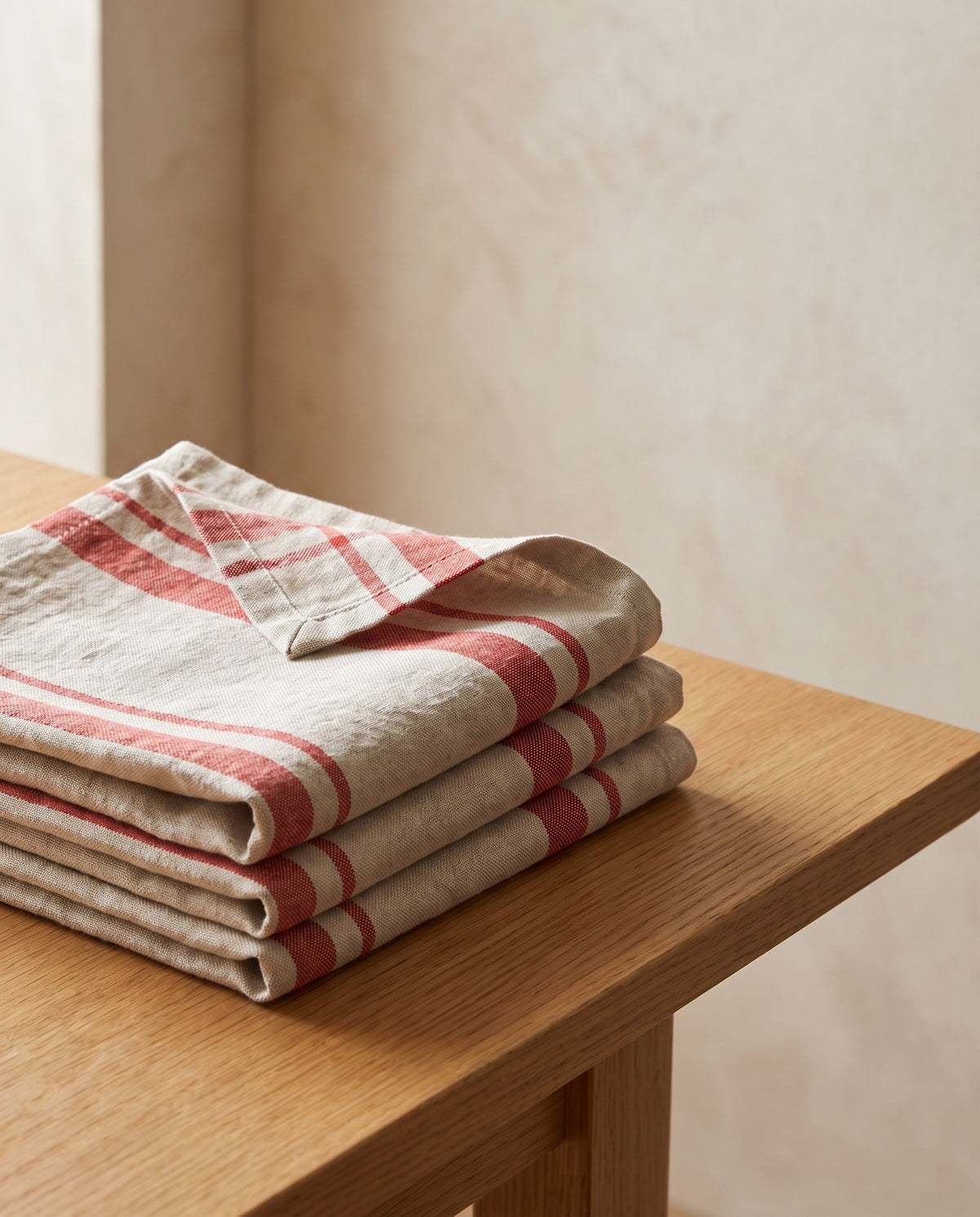 Righe napkins in Pomodoro: four washed linen napkins with red woven stripes, folded and stacked on an oak table